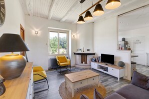 A modern living room with a wooden coffee table, a yellow armchair, a television, and a fireplace.