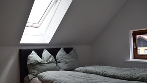 Un dormitorio con tragaluz, cama con almohadas y ventana.