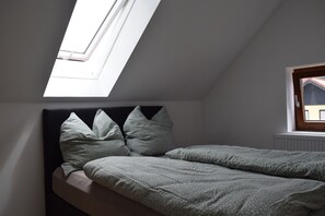 A bedroom with a skylight, a bed with pillows, and a window. - The Blue House - Rhönchalet (Kaltennordheim)