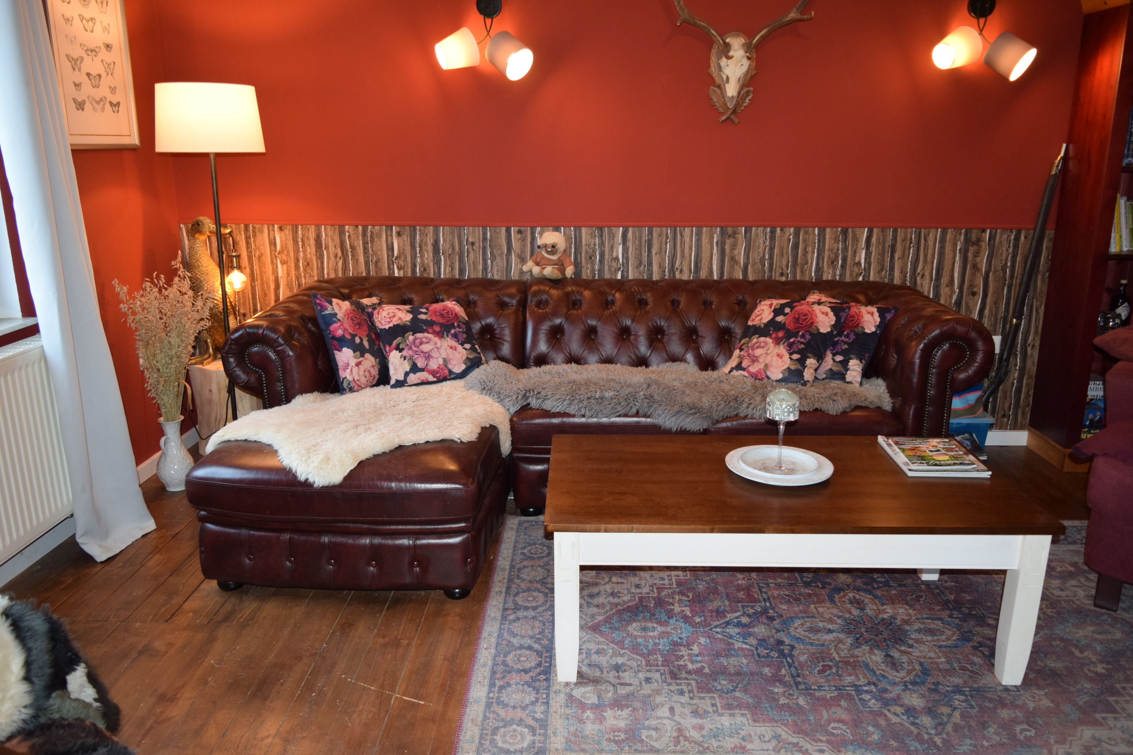 Ein Wohnzimmer mit einer Couch, einem Hocker, einem Couchtisch und einem gemusterten Teppich.