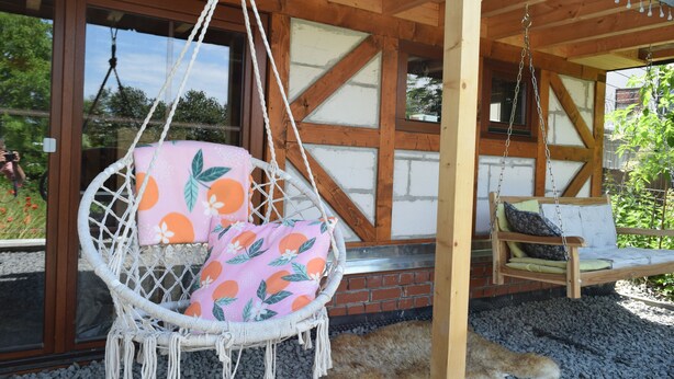 Una estructura de madera con una silla colgante y un banco.