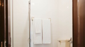 Een badkamer met een douchecabine van glas, een toilet en een wastafel.