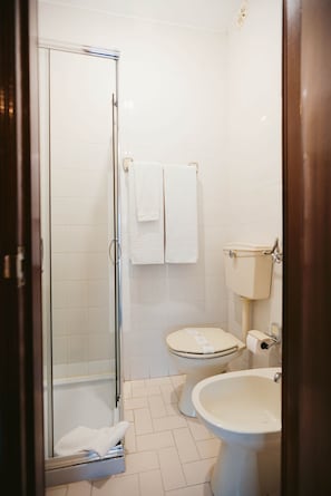 A bathroom with a glass shower enclosure, a toilet, and a sink.