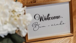 Een lijst met de tekst 'Welcome Bem - nindo', geplaatst op een houten ondergrond met witte bloemen in de buurt.