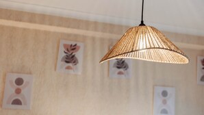 En hängande, vävd lampa i ett rum med mönstrad väggkonst.
