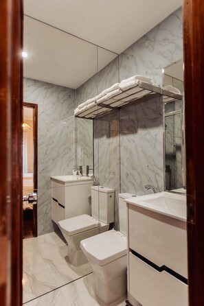 Ein Badezimmer mit Marmorwänden, zwei Toiletten, einem Waschbecken und einem Handtuchhalter.