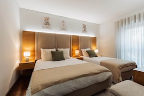 Een hotelkamer met twee bedden, een houten hoofdeinde, nachtlampjes en kunst aan de muur.