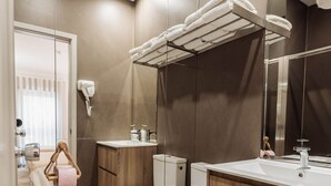 Un bany modern amb un moble de tocador de fusta, una cabina de dutxa de vidre i un vàter.