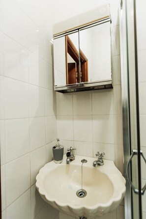 A bathroom with a sink, mirror, and shower. - defaultName (Cabeceiras de Basto)
