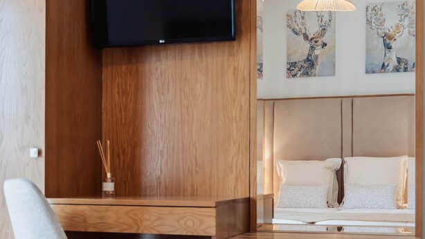 A modern room with a wooden desk, a mounted TV, a chair, and artwork on the wall.