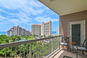 A balcony with a view of a hotel complex, a tennis court, and the ocean. - 🌴Summit at Tops'l 612 | Large Balcony with Gulf Views | Pool | Walk to Beach🌞 (Miramar Beach)
