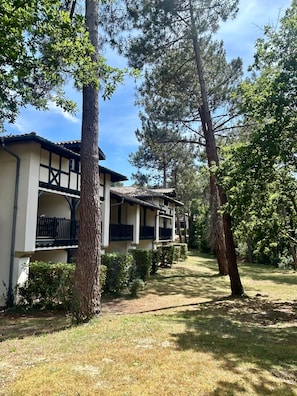 Um edifício com varanda, rodeado por árvores e relva.