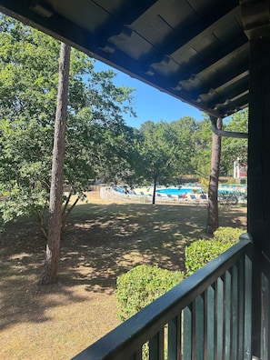 A covered outdoor area with trees, a grassy lawn, and a pool with lounge chairs. - Apartment for 7 in the Heart of Biscarrosse Golf – Pool, Nature & Relaxation (Biscarrosse)