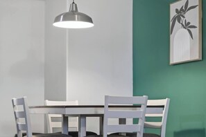 A dining area with a table and chairs, a pendant light, and a framed artwork on the wall. - Feel Energized King Size Bed Fast WiFi 500 Mbps (McAllen)