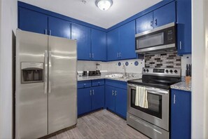 A kitchen with blue cabinets, stainless steel appliances, a microwave, a stove, and a water dispenser. - Feel Energized King Size Bed Fast WiFi 500 Mbps (McAllen)
