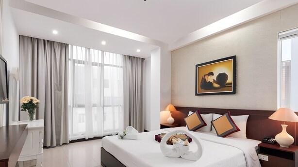 A modern hotel room with a large bed, bedside lamps, a flat-screen TV, and a painting on the wall. - Star Hotel (Da Nang)