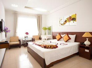 A hotel room with a large bed, a desk, a chair, a TV, and a window with curtains. - Star Hotel (Da Nang)