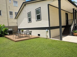 Een gelijkvloers huis met een overdekte patio, een barbecue en een klein terras.