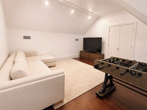 Ein Zimmer mit einer Couch, einem Fernseher und einem Kicker.