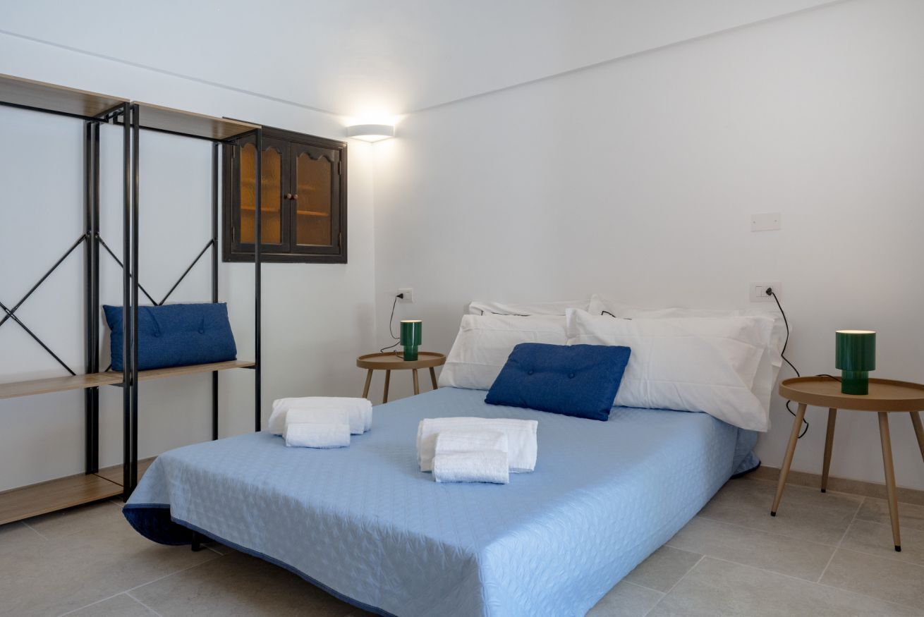 A neatly arranged hotel room with a bed, two bedside tables, and a wall-mounted shelf.