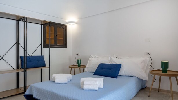 Een verzorgde hotelkamer met een bed, twee nachtkastjes en een wandplank.