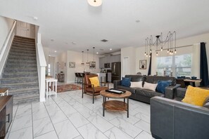 Ein modernes Wohnzimmer mit Treppe, Essbereich und Küche.