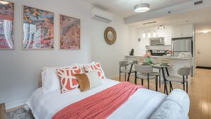 A modern bedroom with a bed, a dining area with a table and chairs, and a kitchenette. - Group-Friendly Old Port Suite | Parking | Sleeps 6 (Montreal)