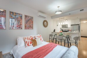 Ein modernes Schlafzimmer mit Bett, einer Essecke mit Tisch und Stühlen sowie einer Küchenzeile.