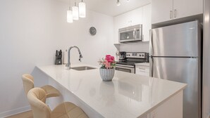 A modern kitchen with a central island, stainless steel appliances, and pendant lighting. - Group-Friendly Old Port Suite | Parking | Sleeps 6 (Montreal)