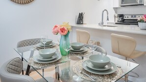 A modern dining area with a glass table, grey plates, and a vase with flowers. - Group-Friendly Old Port Suite | Parking | Sleeps 6 (Montreal)
