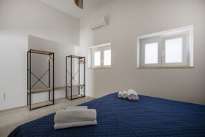 Ein Schlafzimmer mit einem Bett, zwei Kleiderschränken, einem Fenster und einer Klimaanlage.