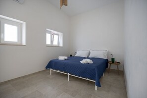 A bedroom with a bed, two windows, a bedside table, and a lamp. - Spacious double bedroom with living area and private bathroom, ideal for two, located within Trulli Italia, a complex of trulli with a shared garden. Surrounded by greenery, the accommodation is located in Selva di Fasano, a quiet and verdant hillside ha (Selva di Fasano)
