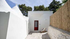 Un patio estrecho con una puerta roja, una pared blanca y una cerca de madera.