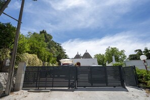 A gated entrance with a white building in the background, surrounded by trees. - Spacious double bedroom with living area and private bathroom, ideal for two, located within Trulli Italia, a complex of trulli with a shared garden. Surrounded by greenery, the accommodation is located in Selva di Fasano, a quiet and verdant hillside ha (Selva di Fasano)