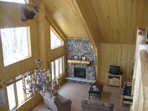 A wooden interior with a stone fireplace, two sofas, a coffee table, and a television.