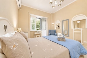 Ein Schlafzimmer mit Bett, Stuhl, Schminktisch und Spiegel.