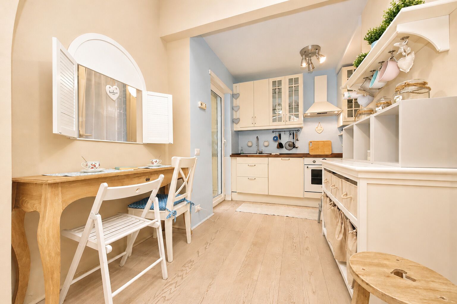 Een keuken met witte kastjes, een houten tafel en een stoel.