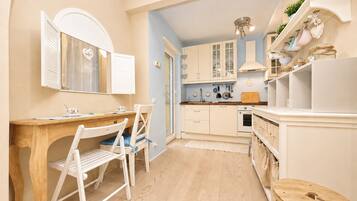 Een keuken met witte kastjes, een houten tafel en een stoel.