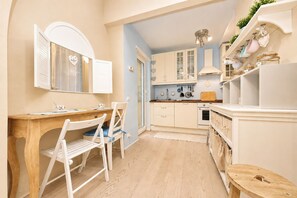 Een keuken met witte kastjes, een houten tafel en een stoel.