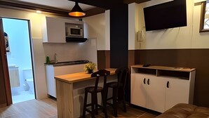 A compact kitchen with a wooden countertop, two bar stools, a microwave, and a TV mounted on the wall. - GTA SANDREAS 402 (Medellín)