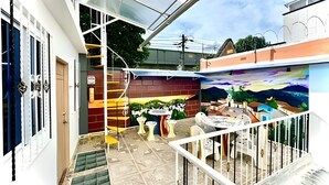 A residential area with a staircase leading to a balcony, a mural on the wall, and a small outdoor seating area. - GTA SANDREAS 402 (Medellín)