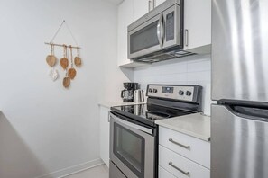 A kitchen with stainless steel appliances, a microwave, oven, and a coffee maker. - 1 BR Old Port| Basilica (Montreal)