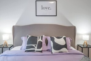 A bed with a headboard, two bedside tables with lamps, and a framed sign on the wall. - 1 BR Old Port| Basilica (Montreal)