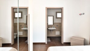 A hotel room with a bed, a bathroom with a sink and mirror, and a view of the outside. - B&B in the heart of Loceri - Apartment (Loceri)