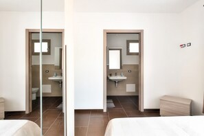 Ein Hotelzimmer mit Bett, einem Badezimmer mit Waschbecken und Spiegel sowie Blick nach draußen.