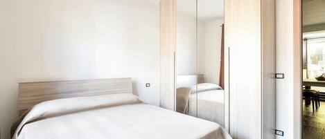 Une chambre à coucher avec un lit, une armoire et un miroir.