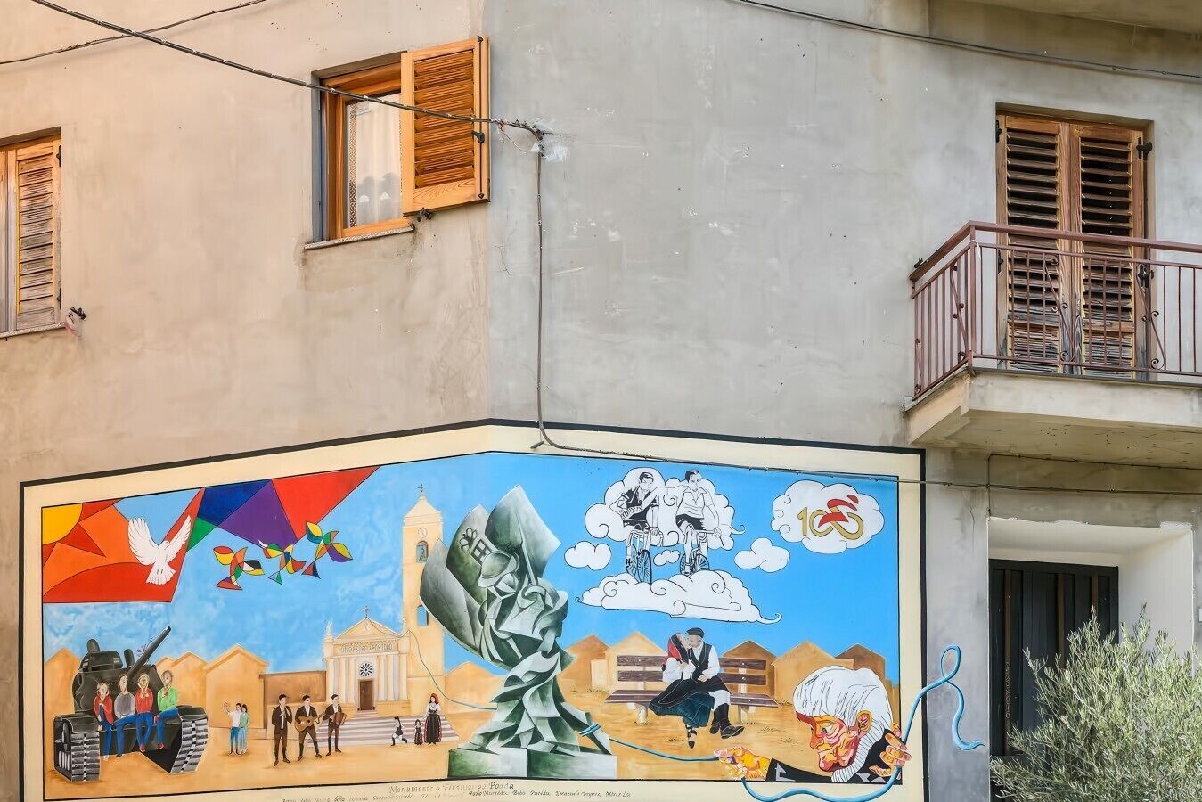 A mural with various figures and symbols, a balcony, and a building facade.