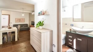 A modern bathroom with a large mirror, a white sink, and dark cabinets. - B&B in the heart of Loceri - Apartment (Loceri)