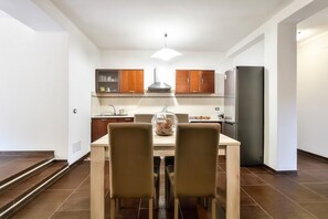 Eine moderne Küche mit Holzschränken, einem Esstisch mit zwei Stühlen und einem Kühlschrank.