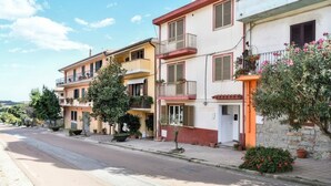 A row of residential buildings with balconies, potted plants, and a clear sky. - B&B in the heart of Loceri - Apartment (Loceri)